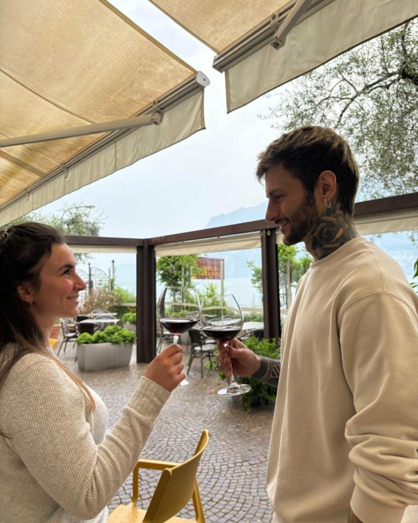 Couple toasting with red wine glasses at outdoor restaurant with a view. Celebrating special occasion.