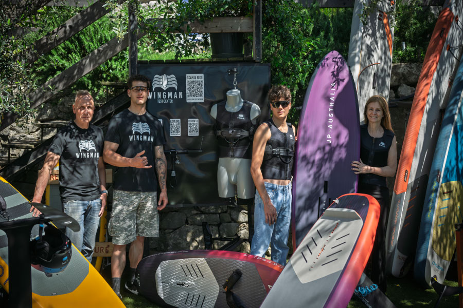 Wingman sport test center with team members, gear, and surfboards, promoting watersport adventures and equipment.